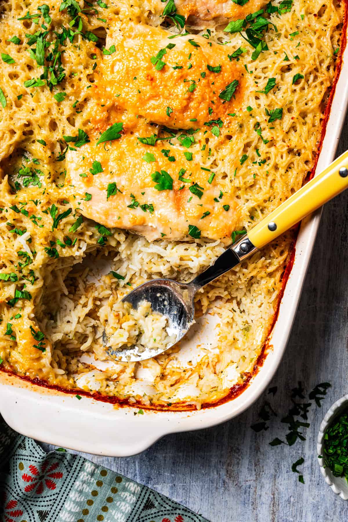 Photo of a chicken and rice casserole, with a serving spoon resting in the space where a chicken breast was served.