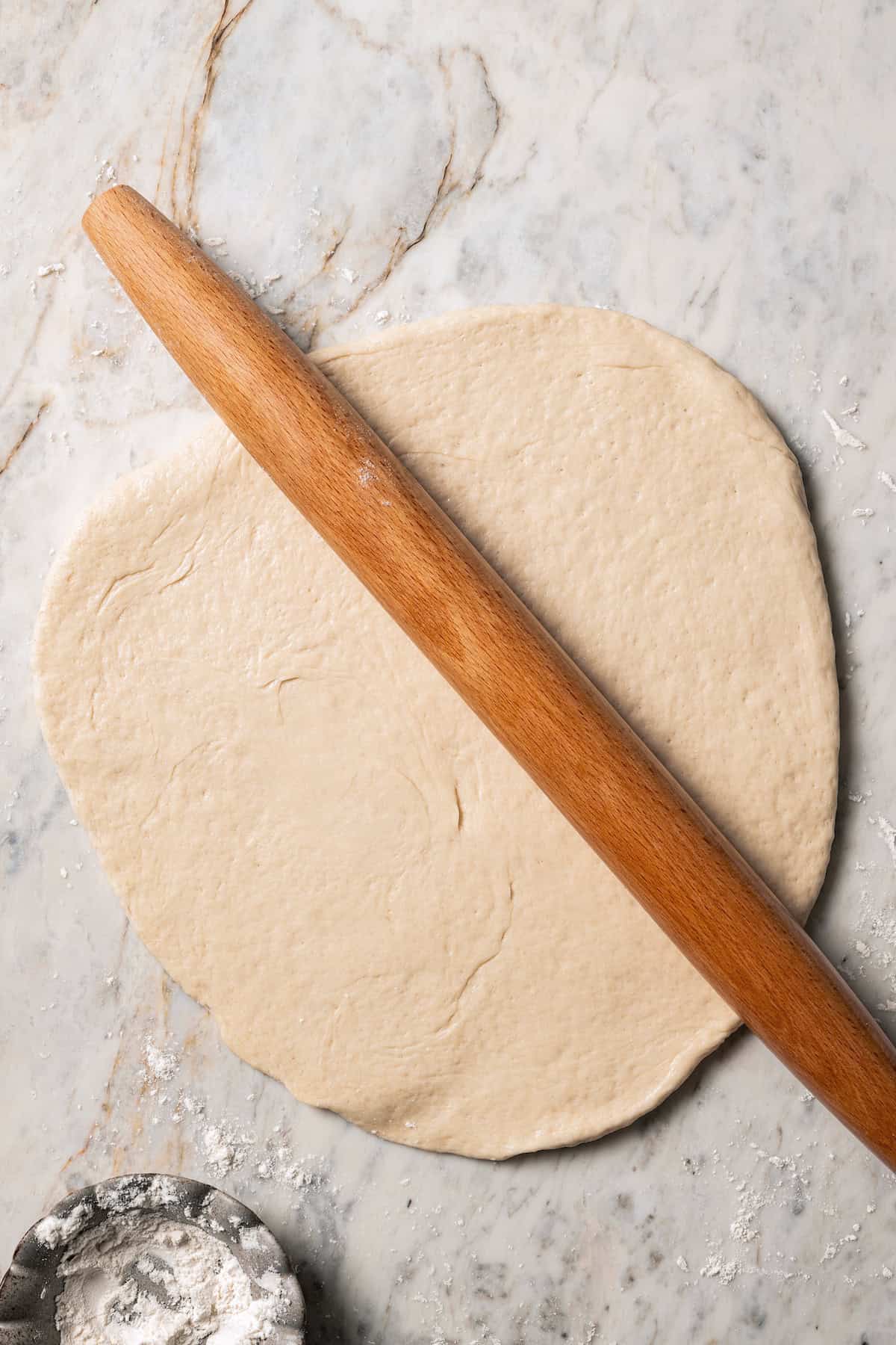 Rolled out bao dough with a wooden rolling pin.