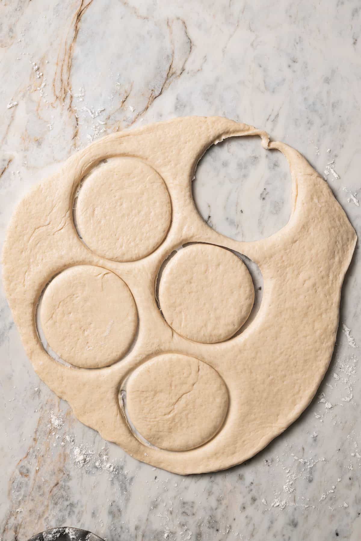 Rolled out bao dough with partially cut out circles, and one fully cut out circle.