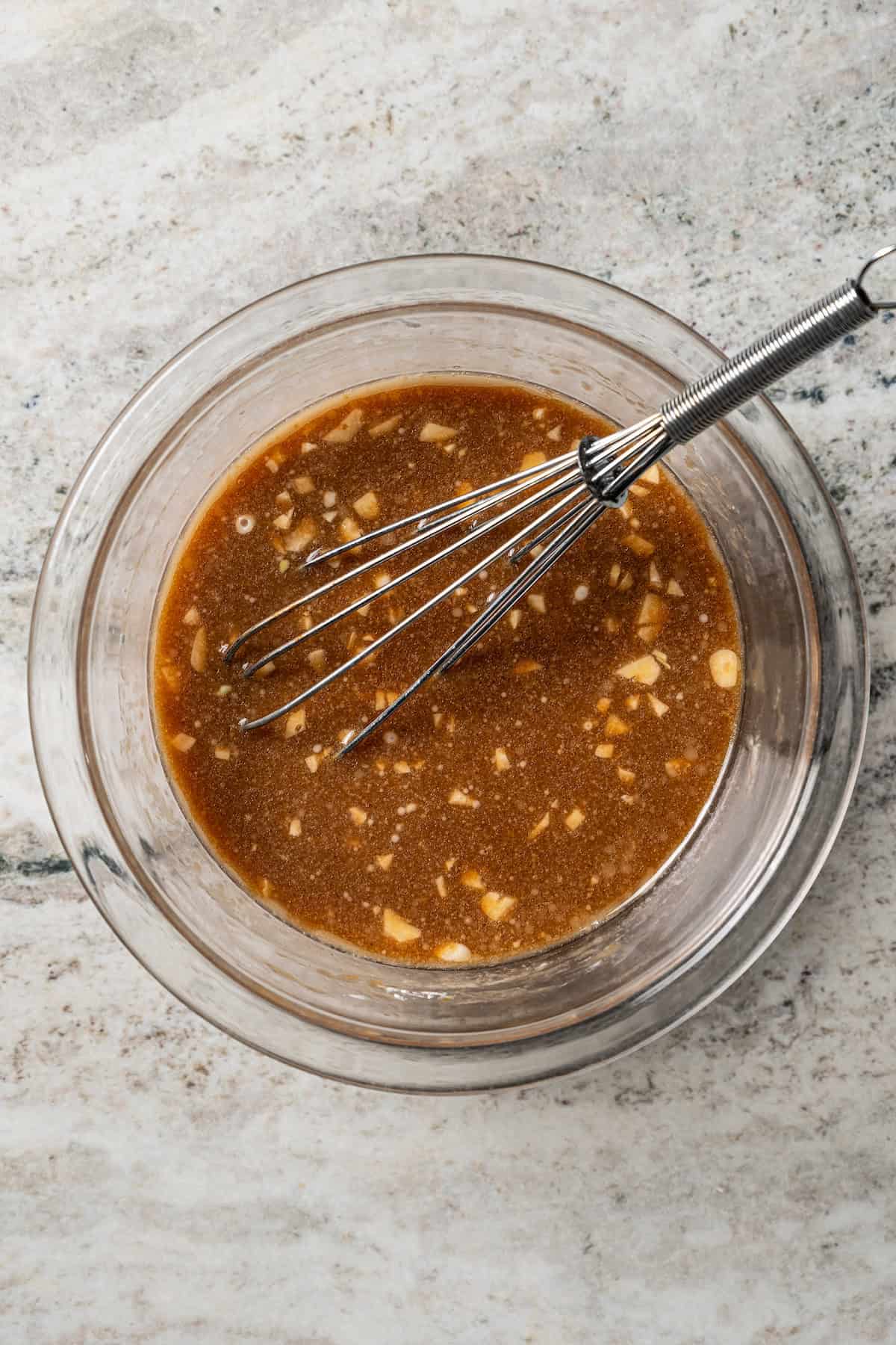 Marinade in a glass bowl with a whisk.