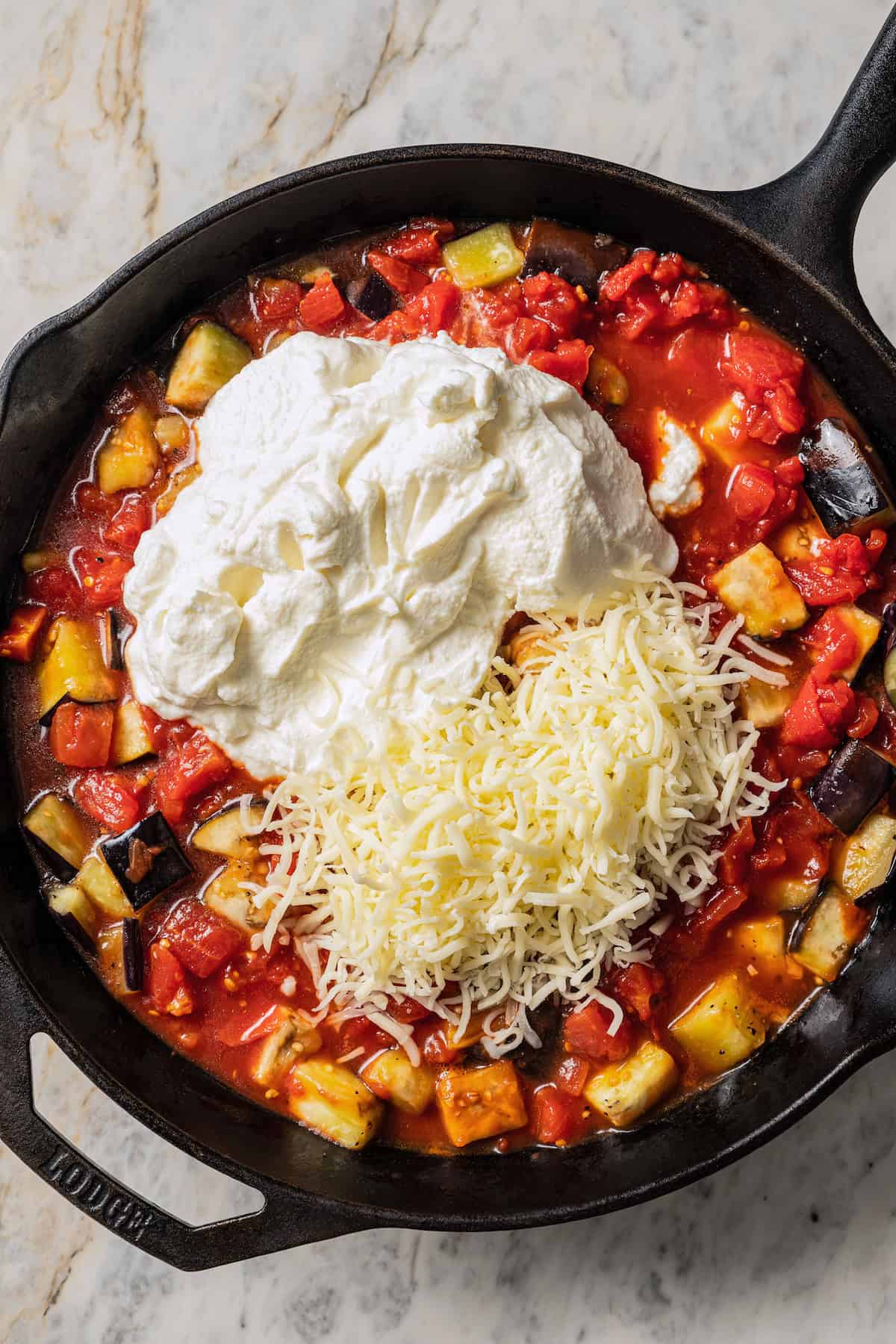 Tomatoes, ricotta, and shredded mozzarella added to a skillet with sauteed eggplant.