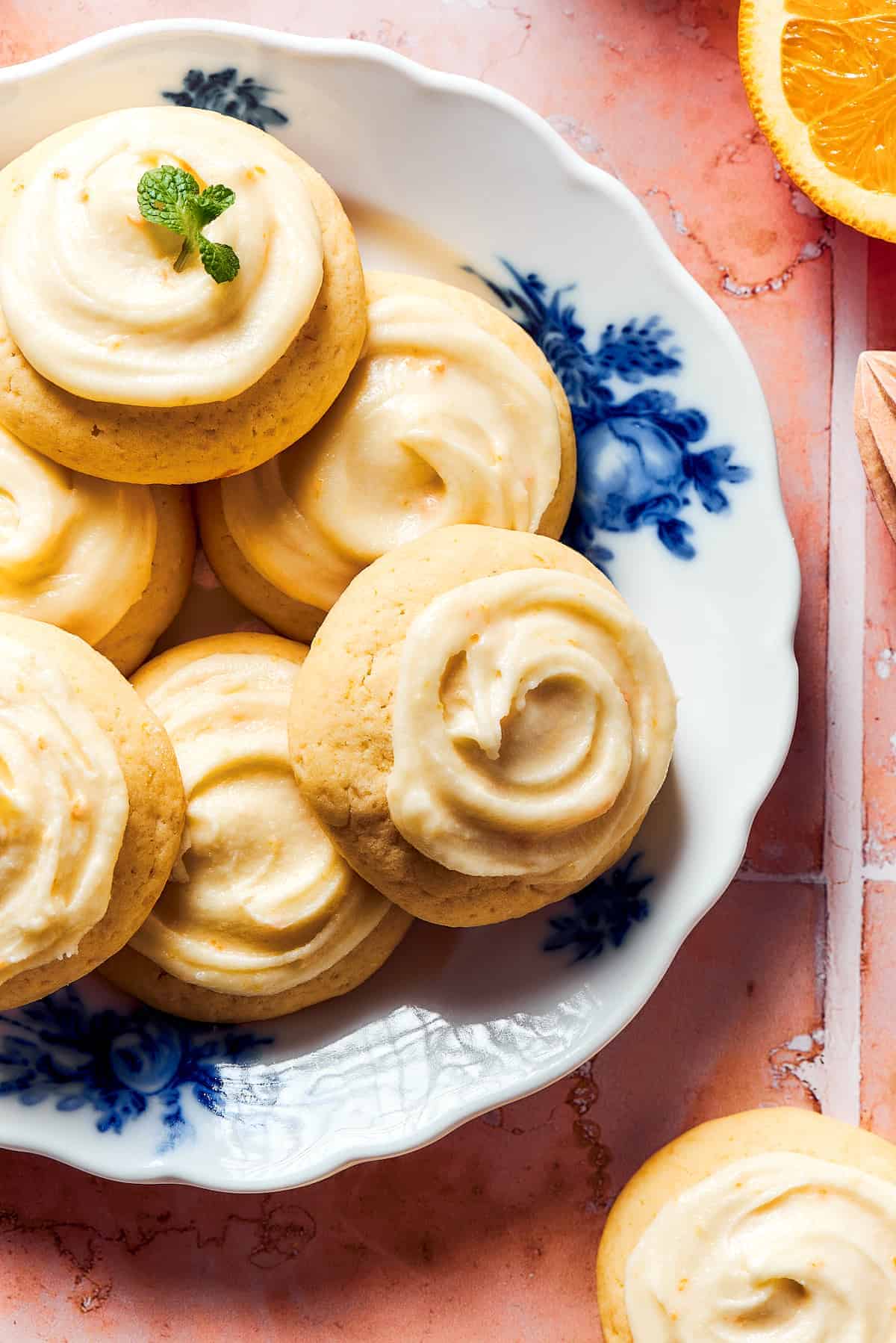 Several homemade orange cookies topped with icing and served on a dessert plate.