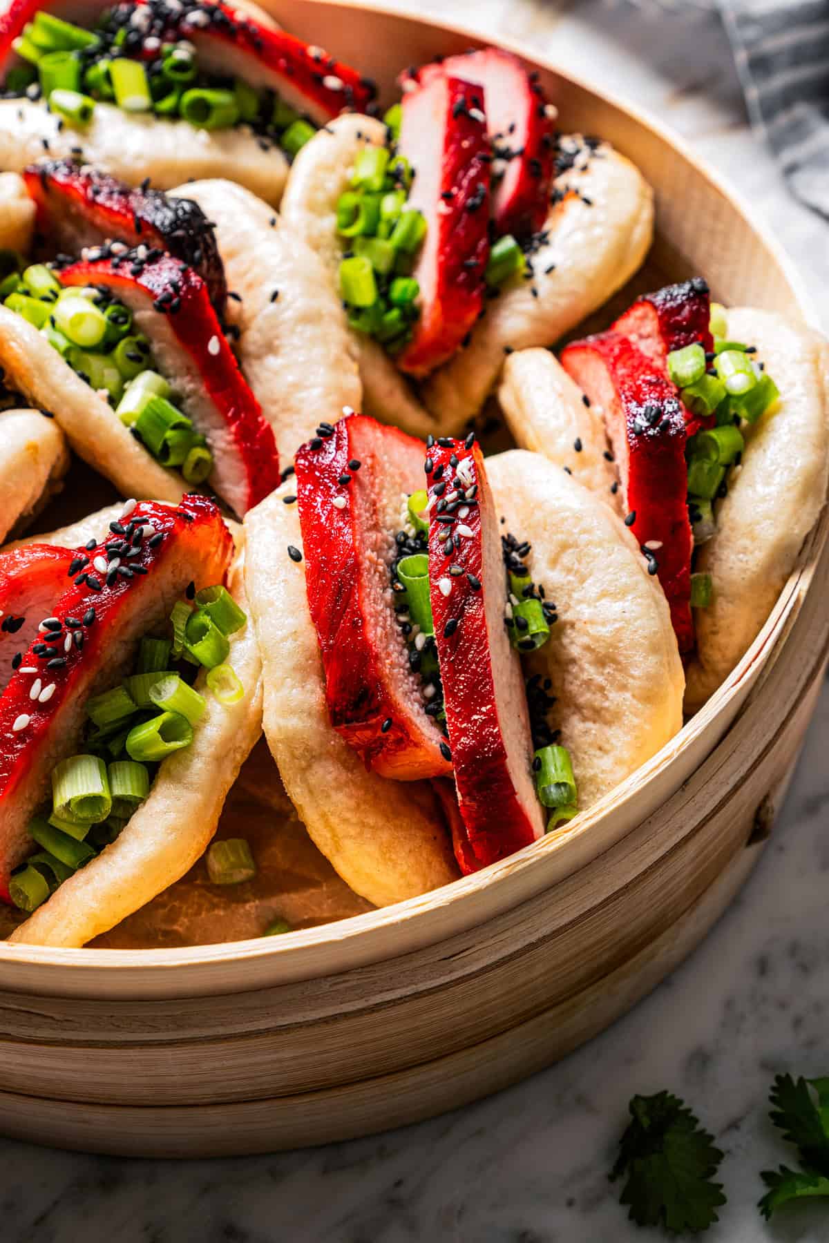 Closeup of char siu bao in a bamboo steamer basket.