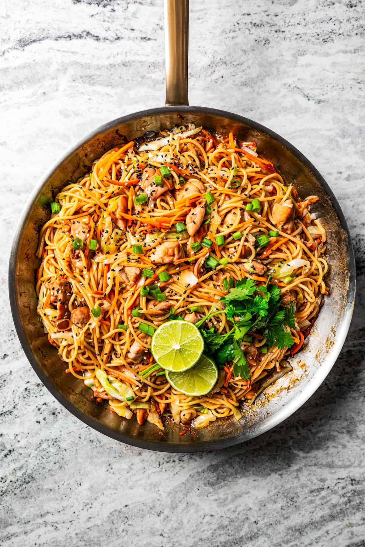 Cooking chicken lo mein in a skillet.