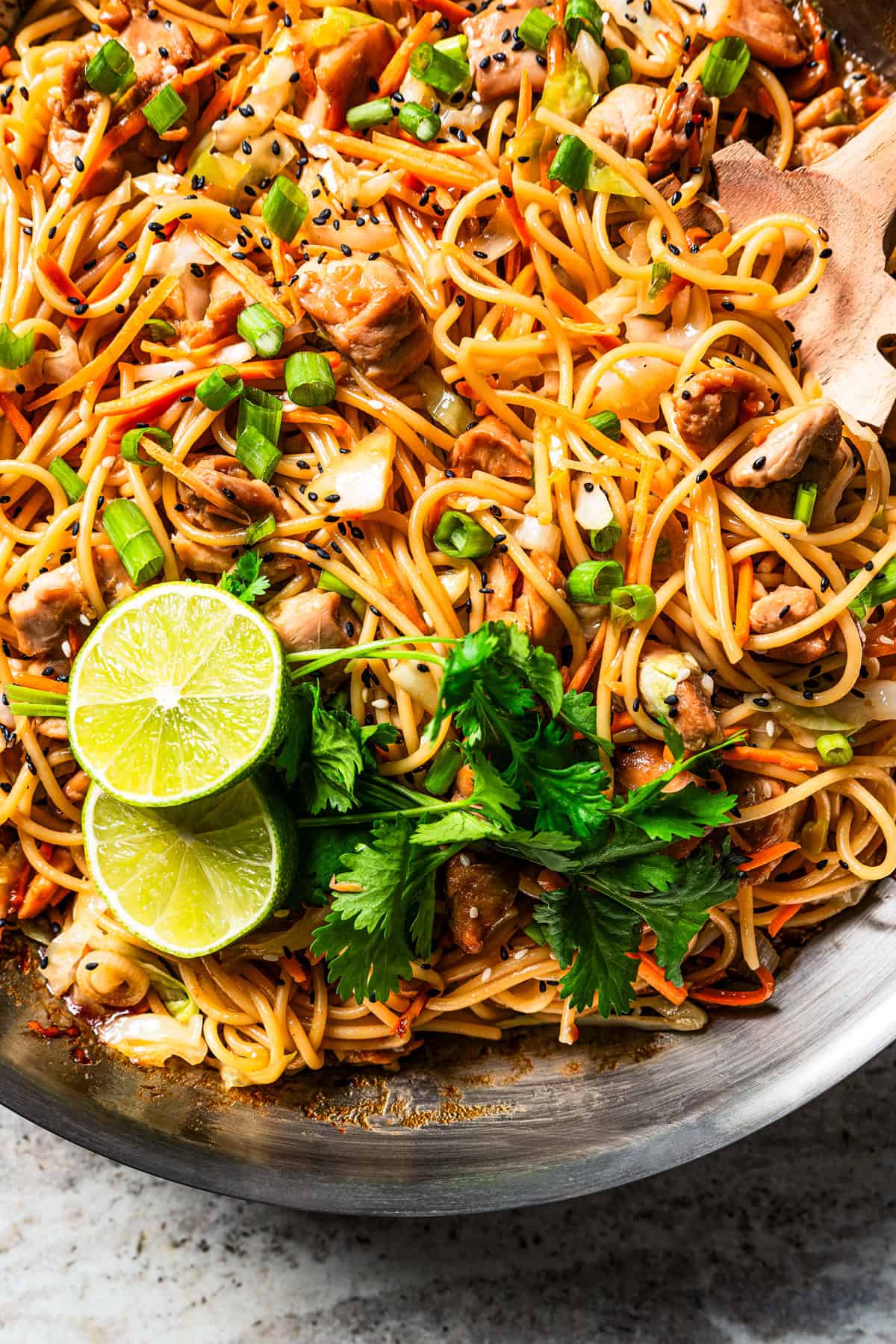 Closeup photo of lo mein noodles tossed with bites of chicken.