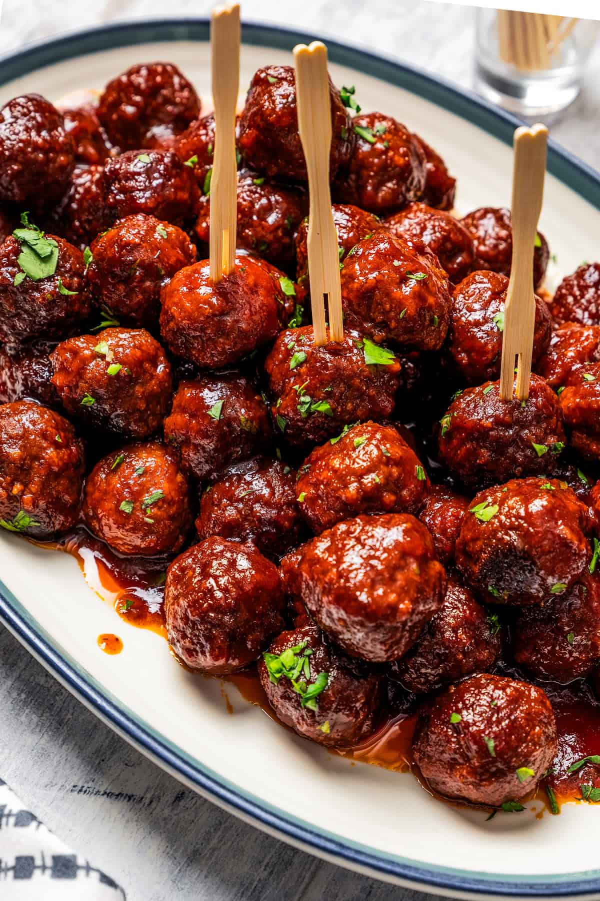 A platter of grape jelly meatballs, some stuck with cocktail skewers.