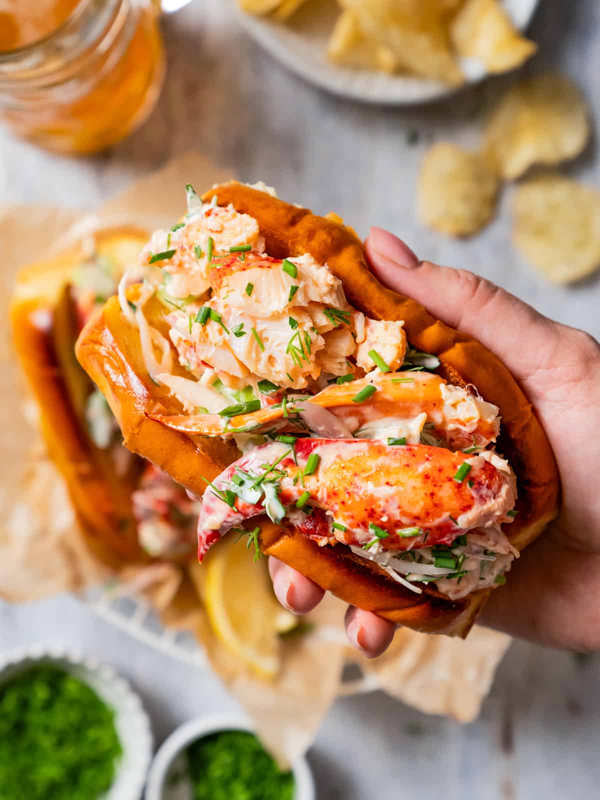 A hand holding up a lobster roll.