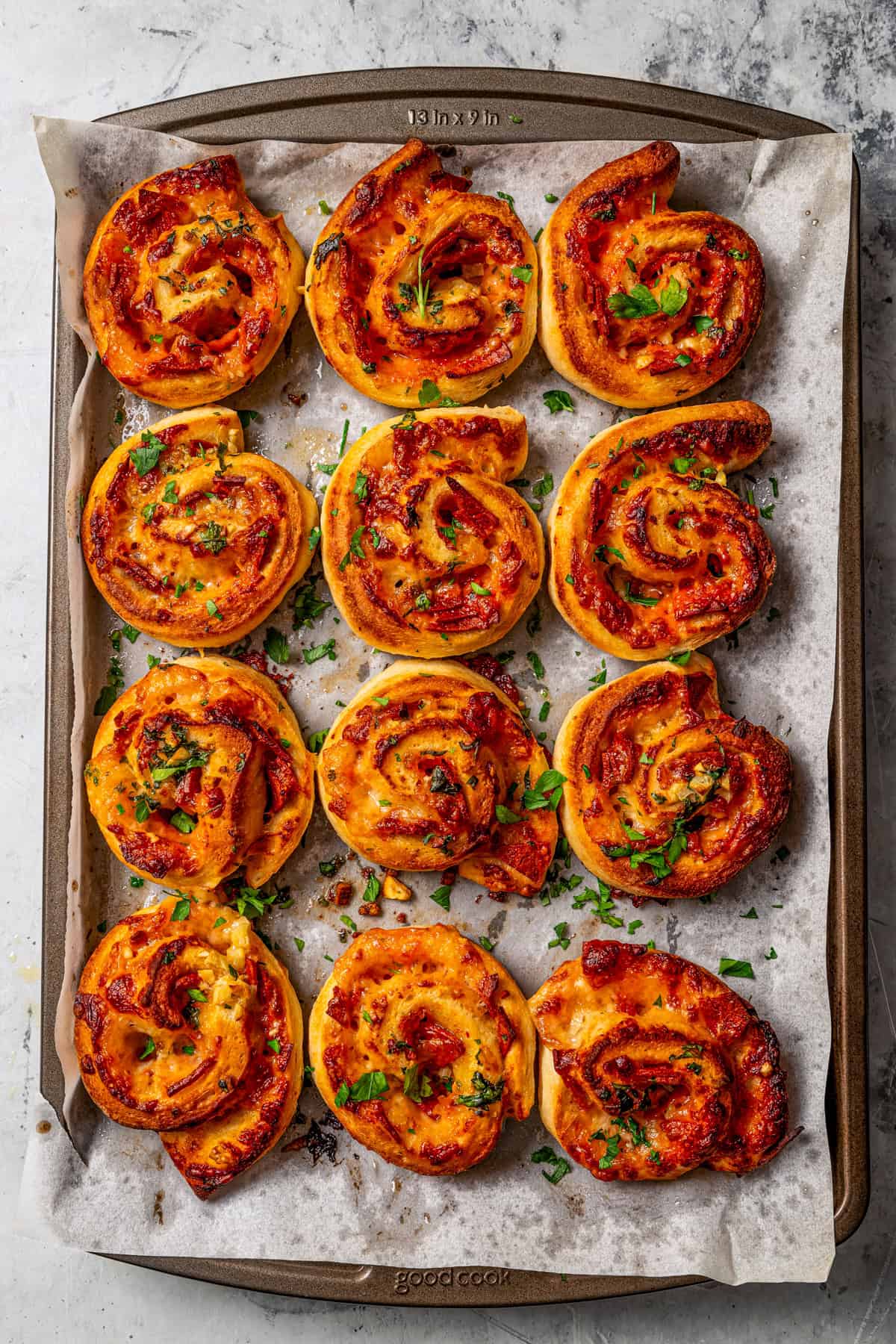 Rows of pepperoni pizza rolls arranged on a parchment-lined baking sheet.