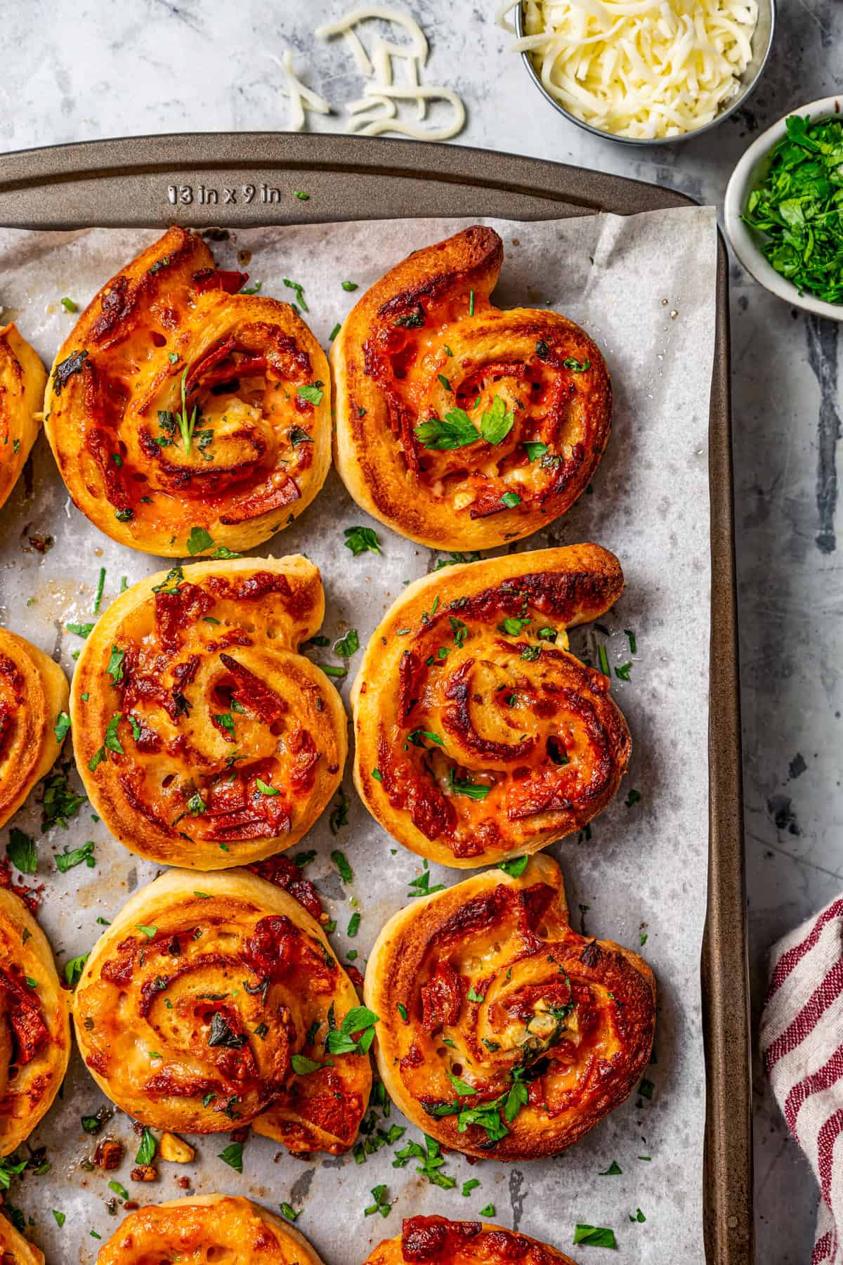 Overhead view of pepperoni pizza rolls on parchment-lined a baking sheet.