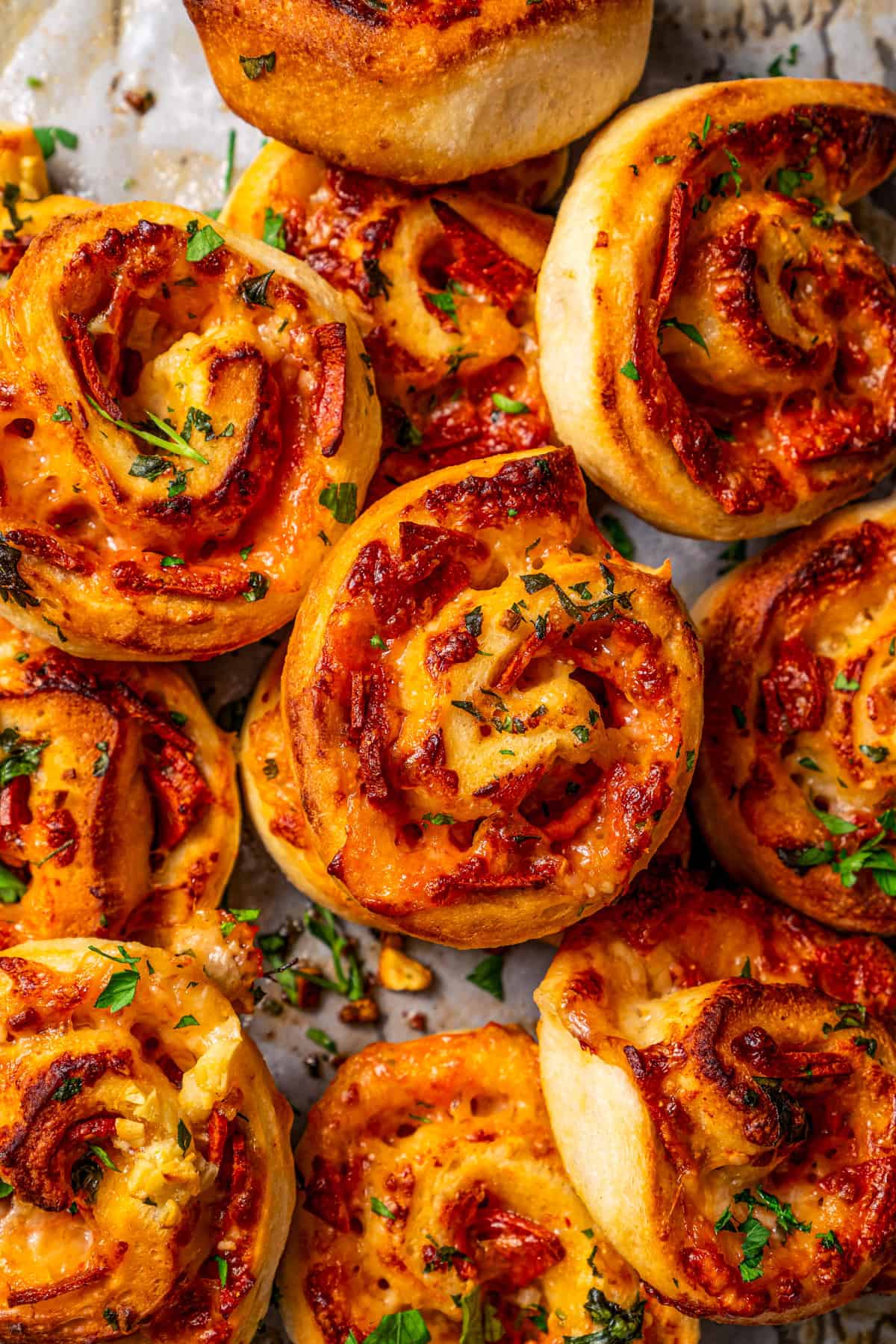 Close-up photo of assorted pepperoni pizza rolls piled on a counter.