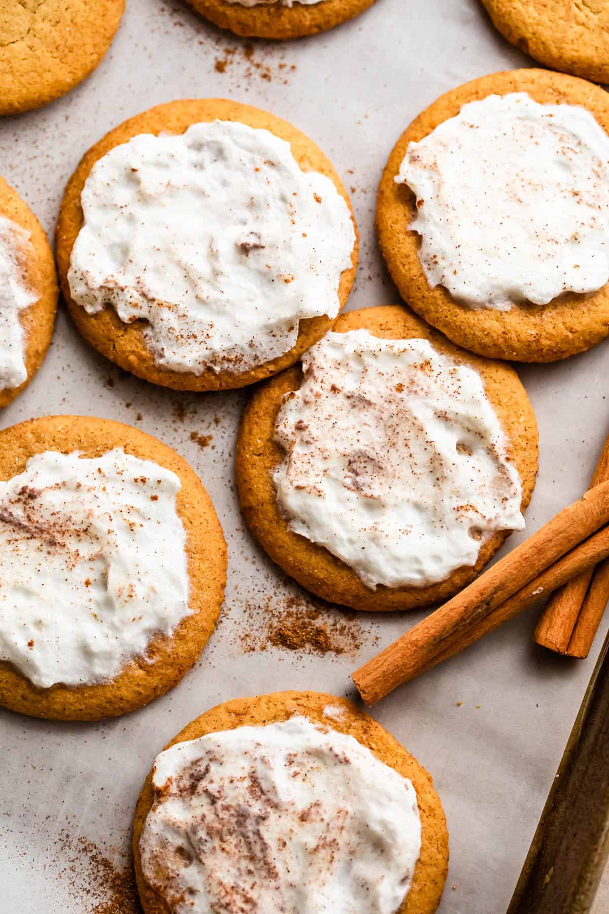 Frosted Pumpkin cookies arranged on parchment paper.