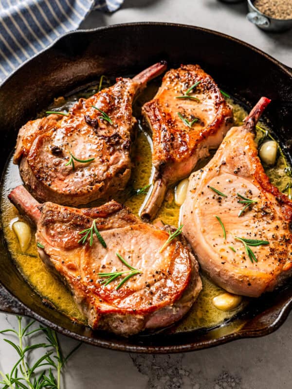 Four seared tomahawk pork chops in a skillet.