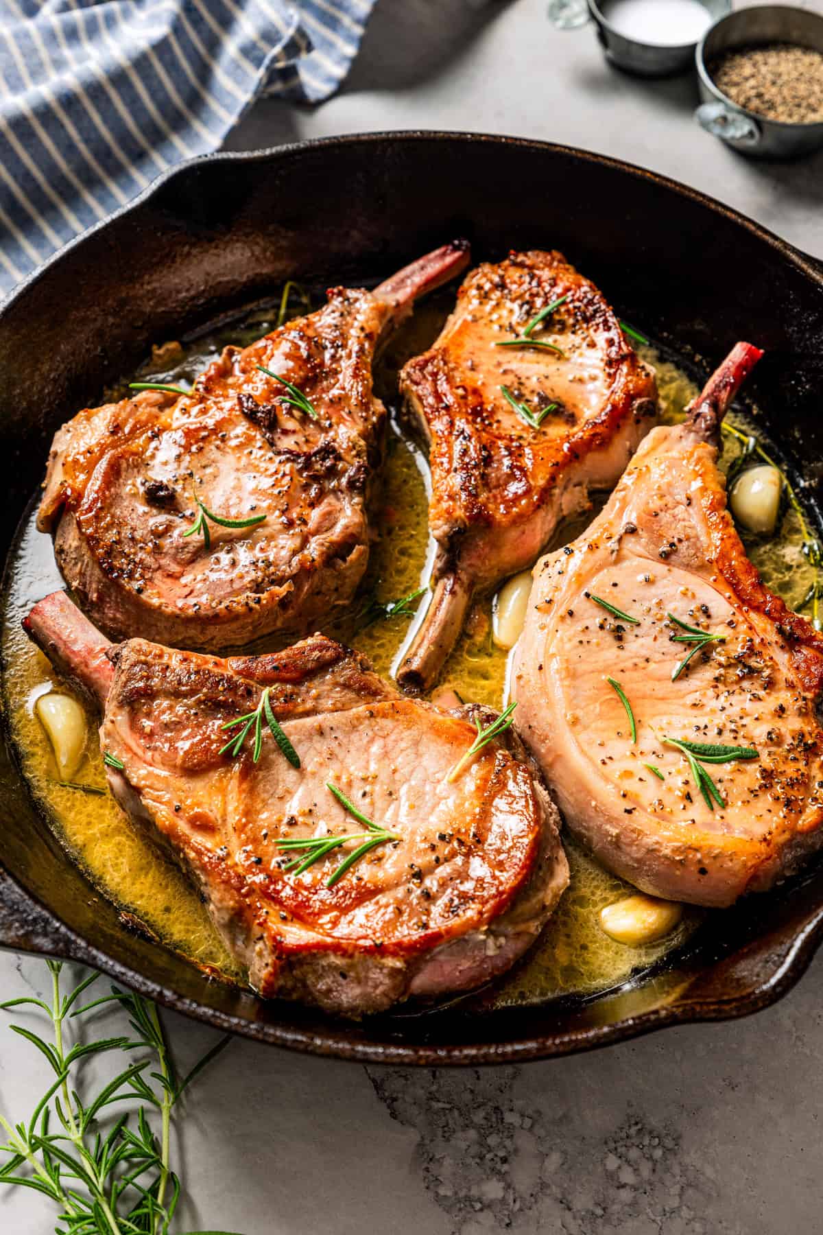 Four seared tomahawk pork chops in a skillet.