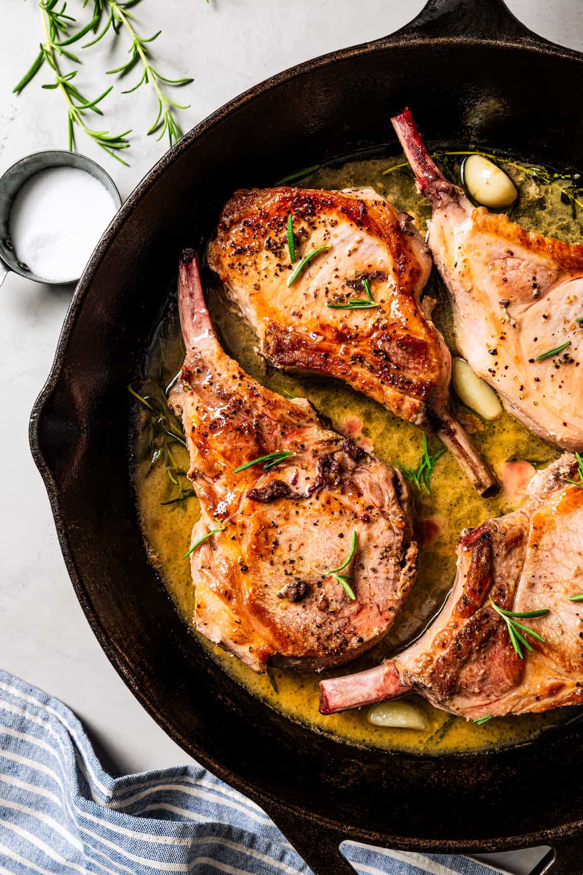 Four seared tomahawk pork chops in a skillet.