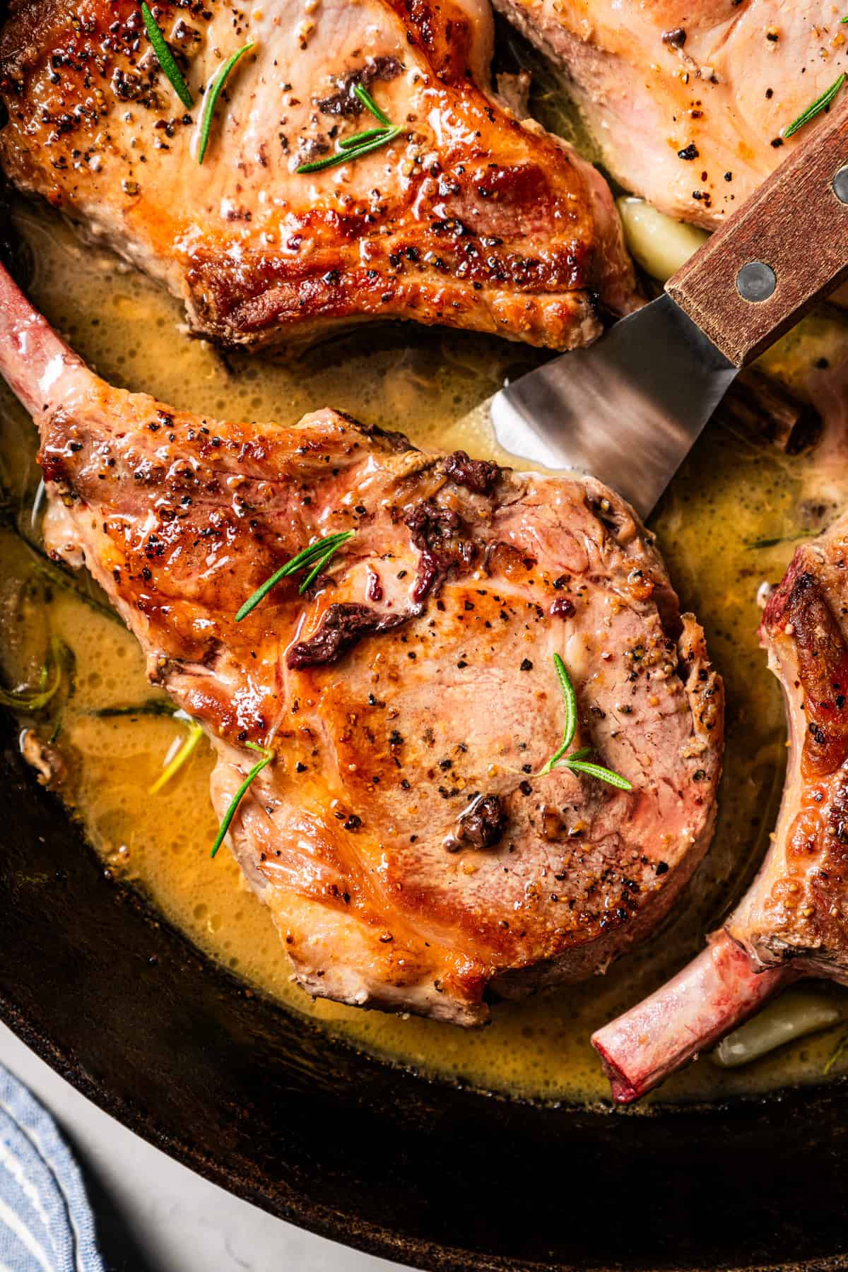 Juicy tomahawk pork chops are easy to cook and look amazing on a plate! These are pan-seared and basted with butter, locking in the flavor. Close up of tomahawk pork chops.