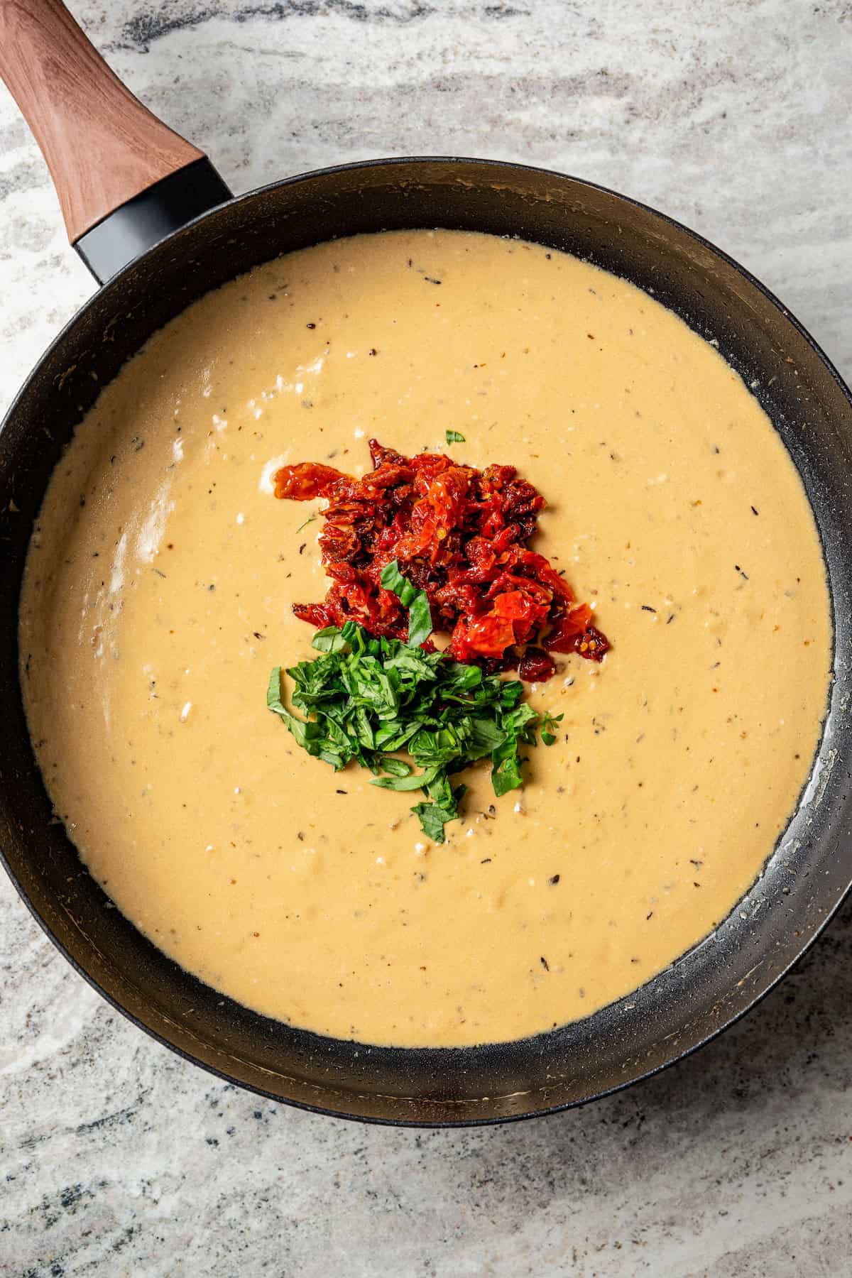 Sundried tomatoes and basil added to lemon butter sauce in a skillet.