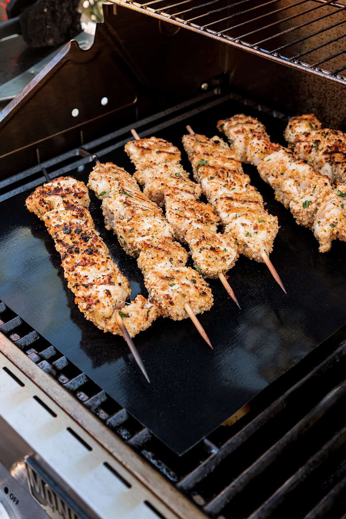 Chicken spiedini cooking on a grill.