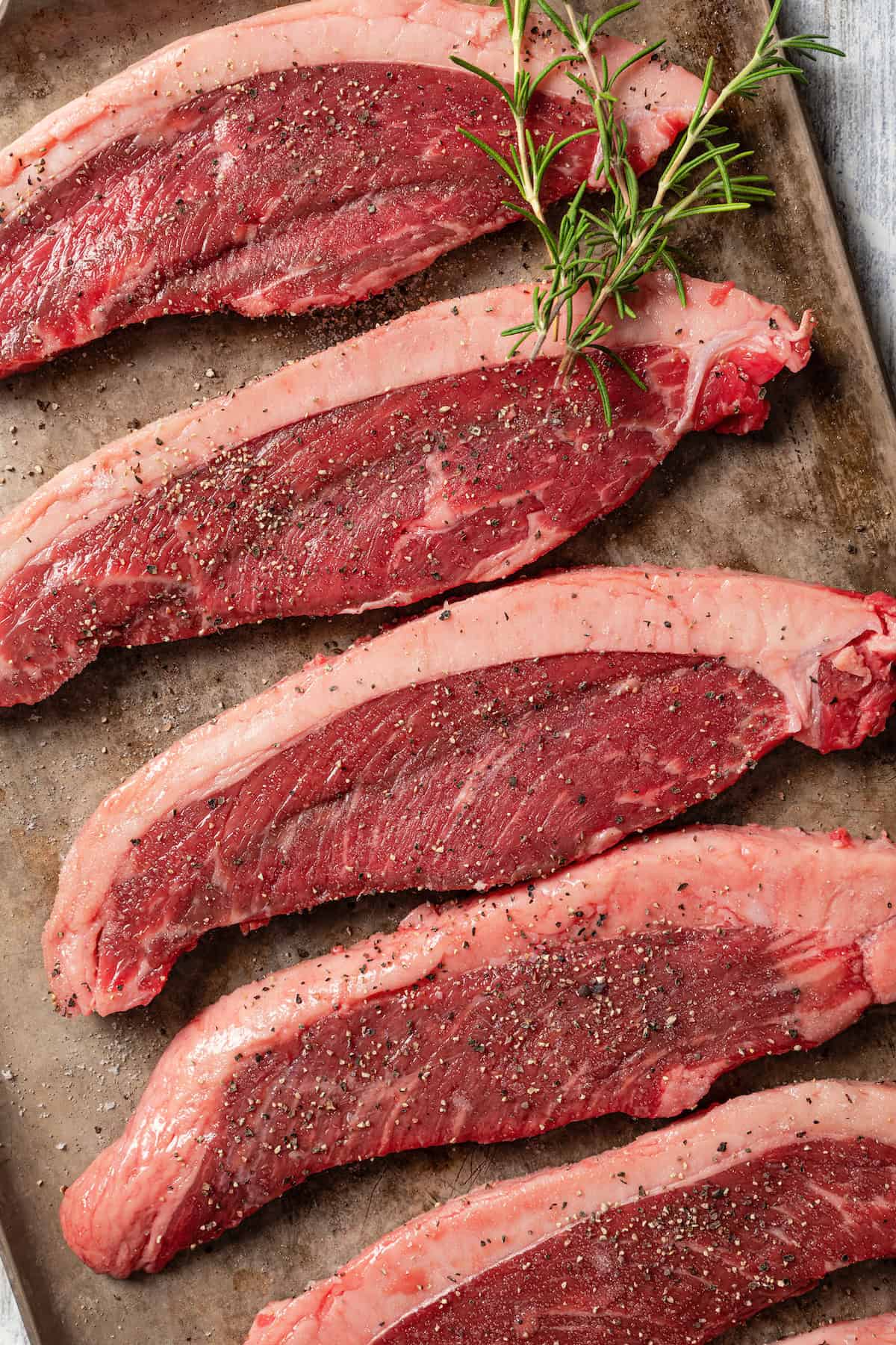 Slices of coulotte steak on a baking pan.