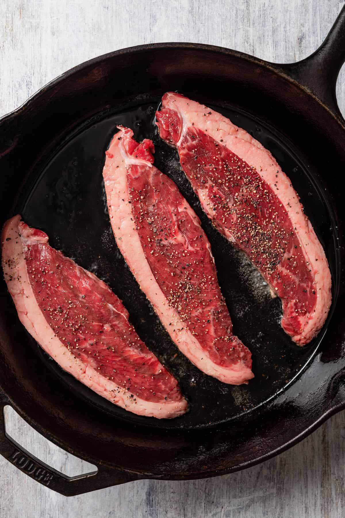 Raw coulotte steaks in a pan.