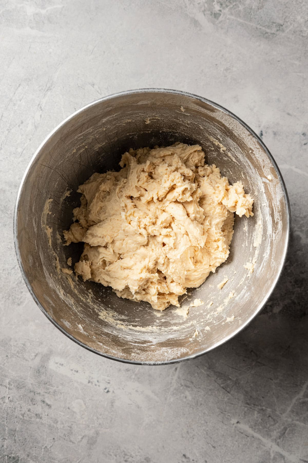 Dinner roll dough coming together in a mixing bowl.