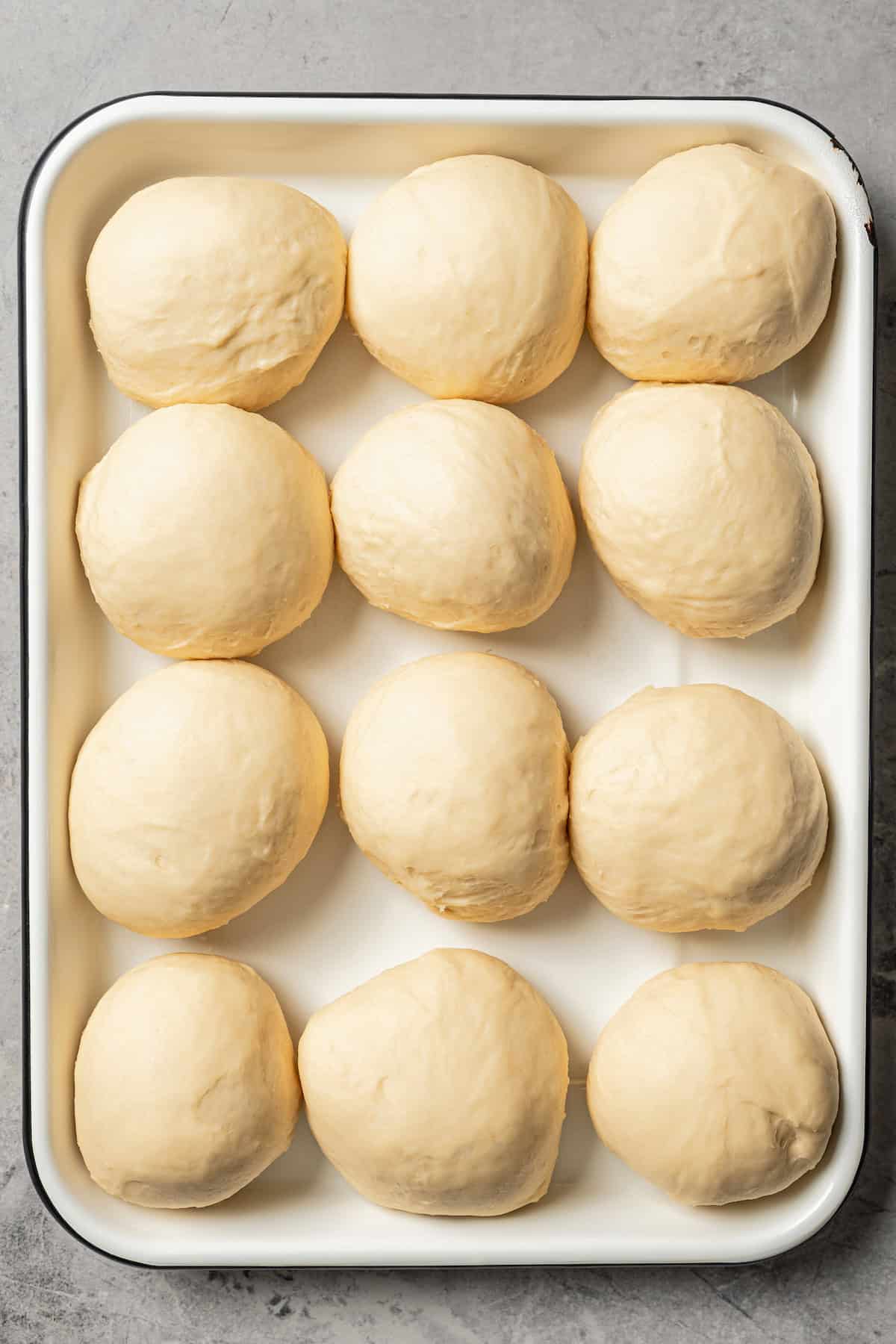 Unbaked dinner rolls on a baking sheet.