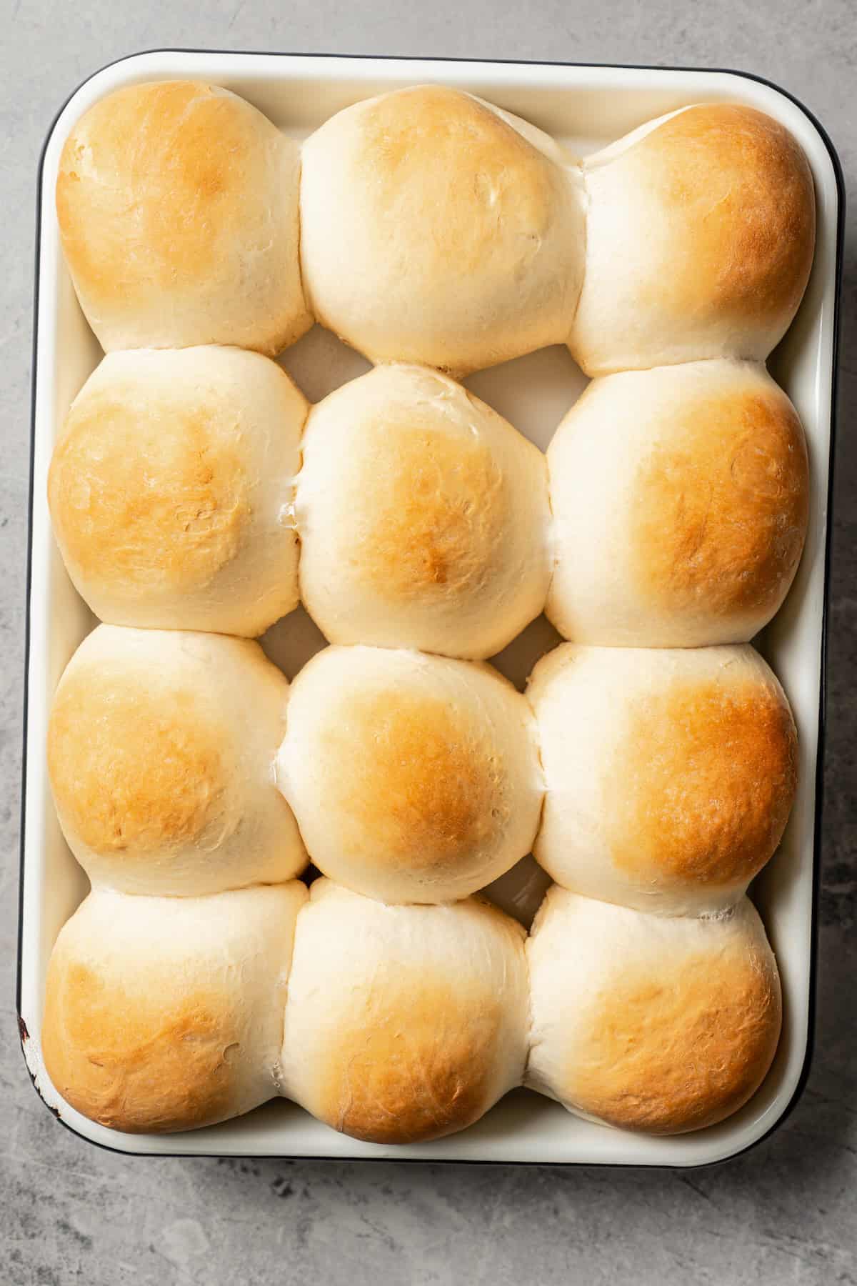 Freshly baked dinner rolls on a metal baking sheet.