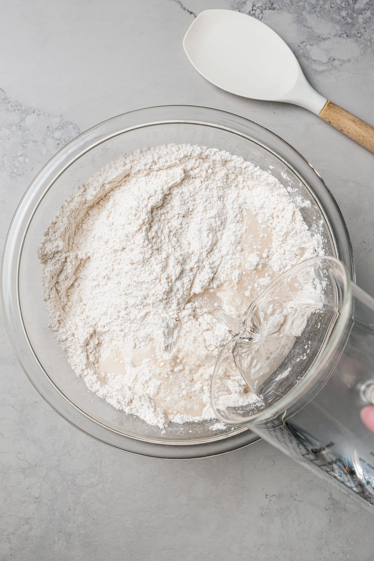 Water being added to the dry ingredients in a glass bowl.