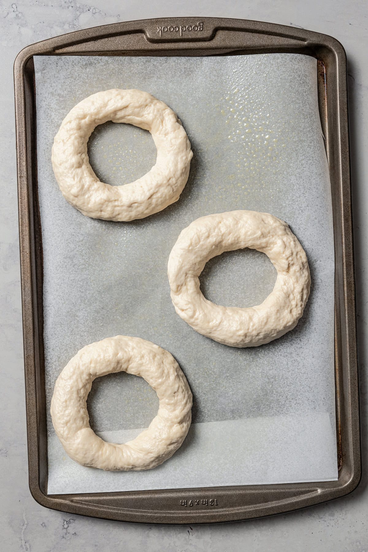 Three dough rings on a lined baking sheet.