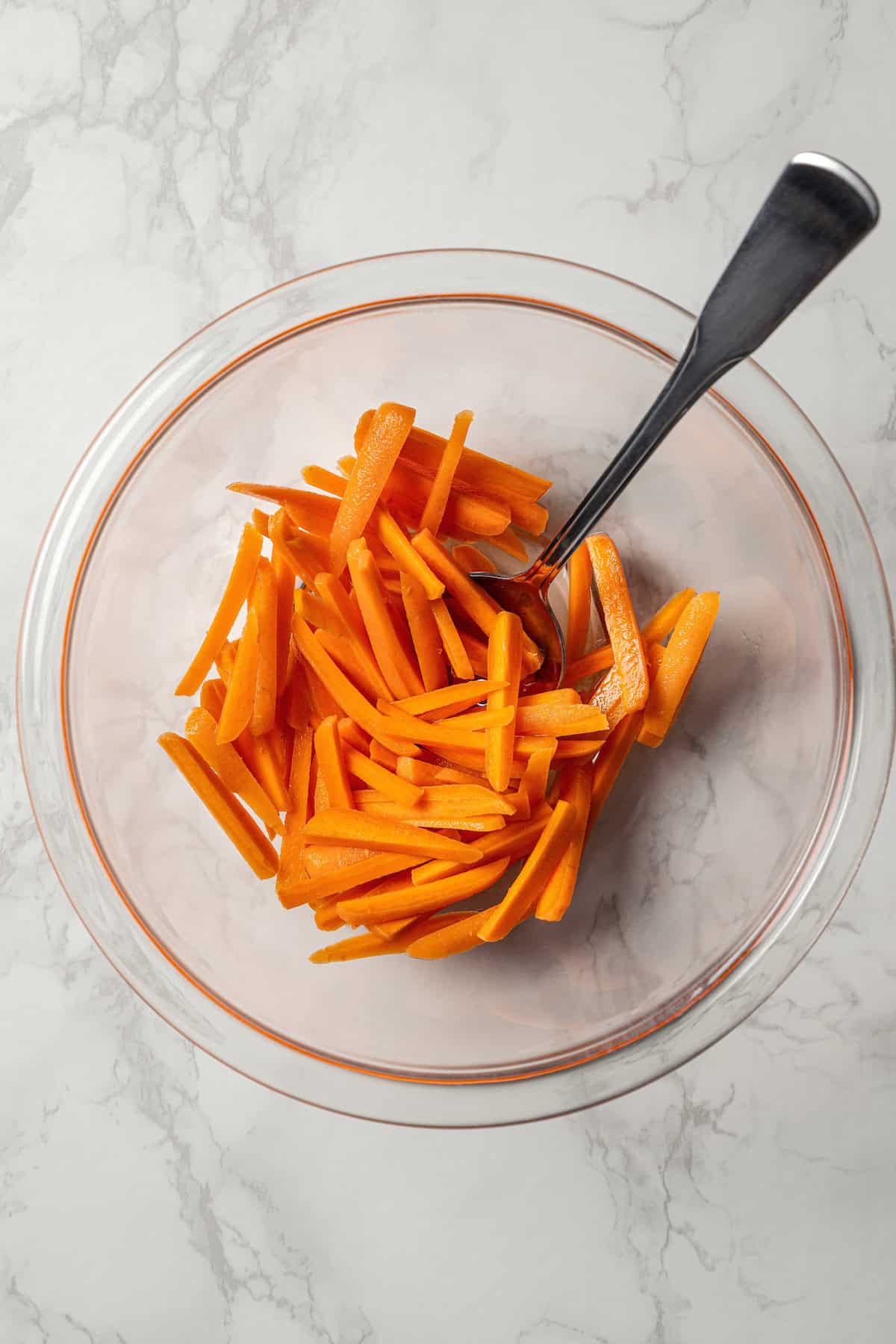 Thinly sliced carrots in a glass bowl.