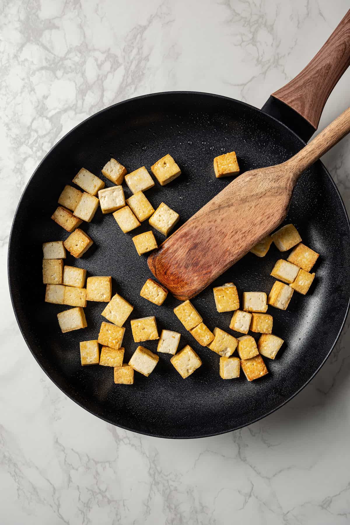 Golden cooked tofu cubes in a skillet.