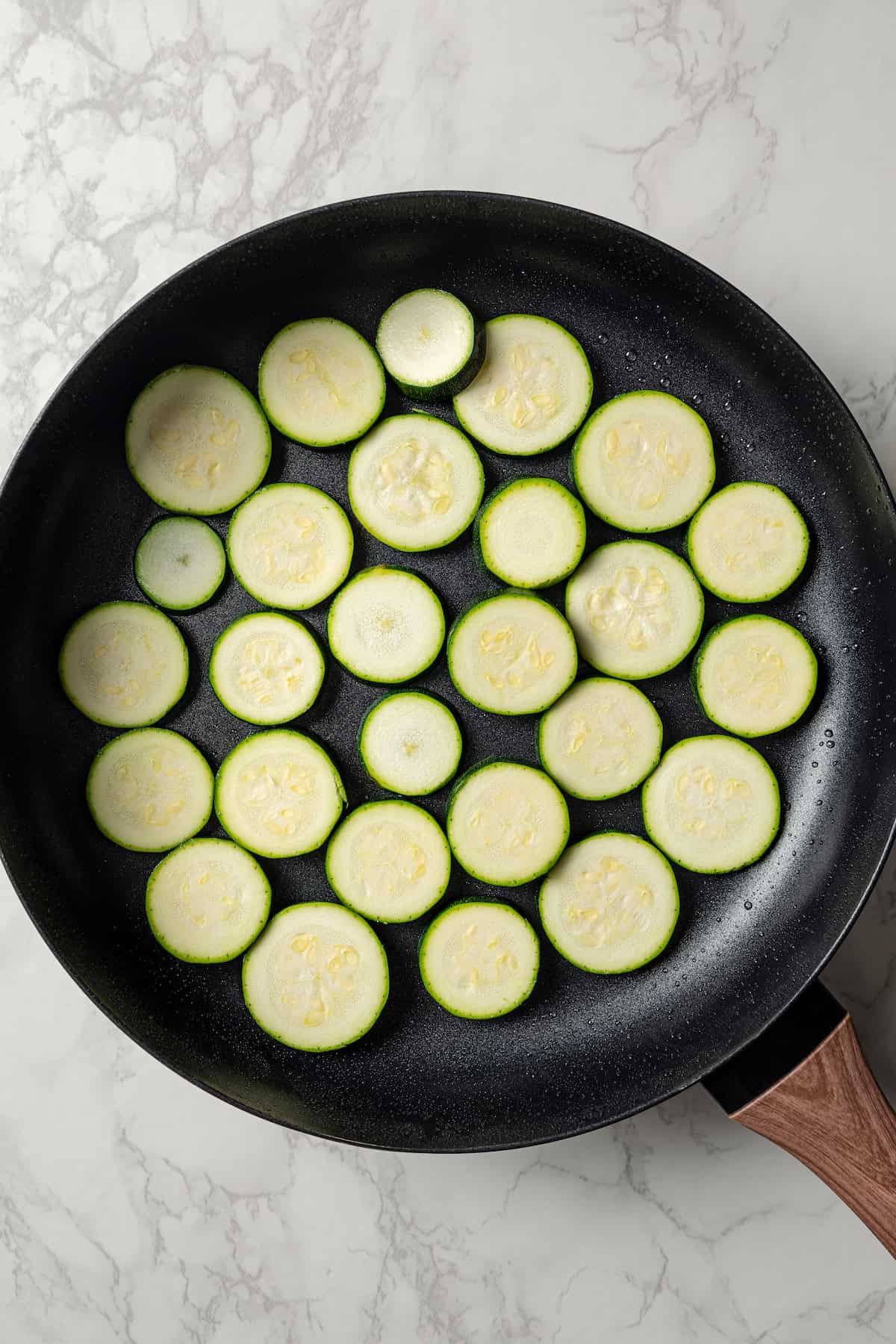 Zucchini slices in a skillet.