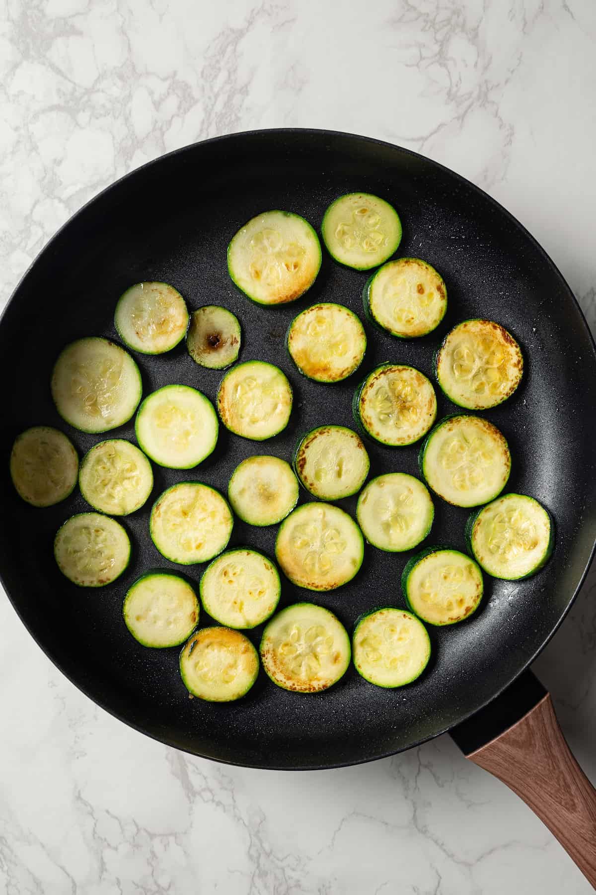 Cooked zucchini slices in a skillet.