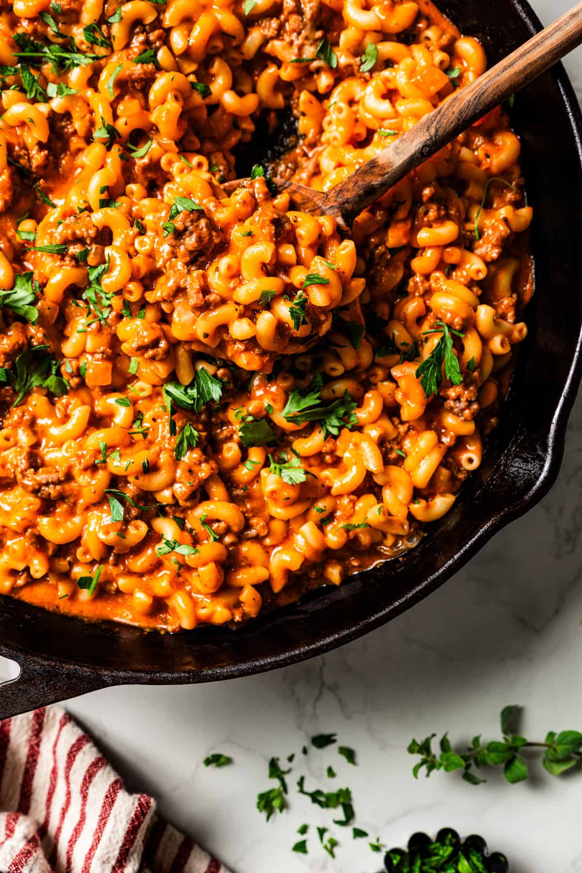 Beefaroni in a large skillet with a wooden serving spoon stirring through it.