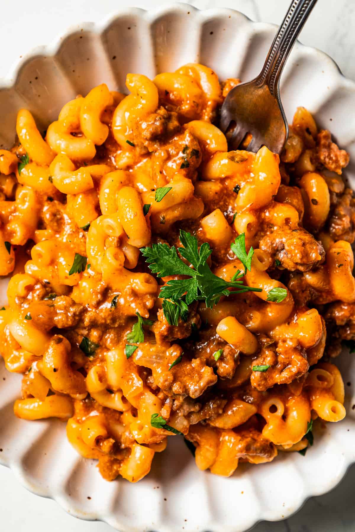 Ground beef mixed with macaroni pasta and served in a bowl.