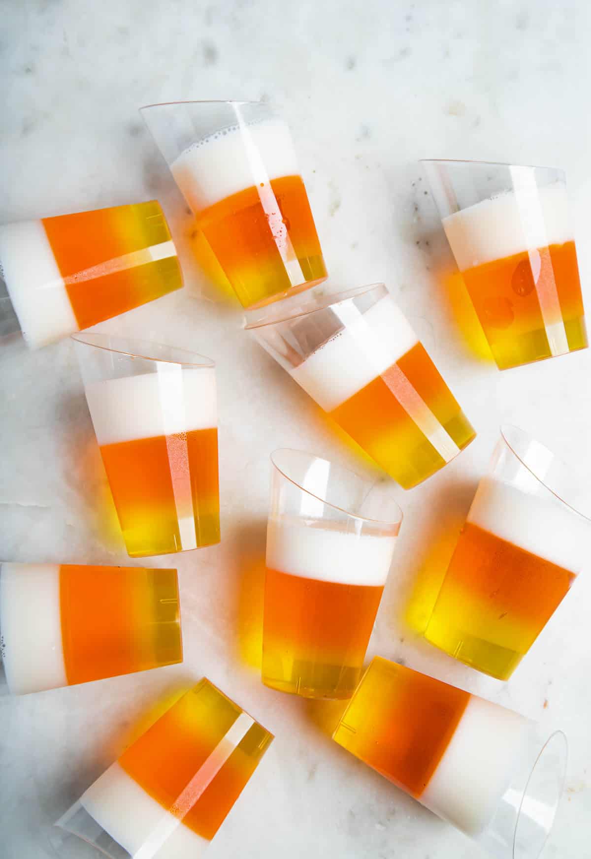 Homemade Candy corn jello shots arranged on a white surface.