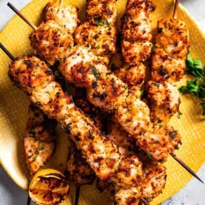 Chicken spiedini skewers arranged on a yellow plate.