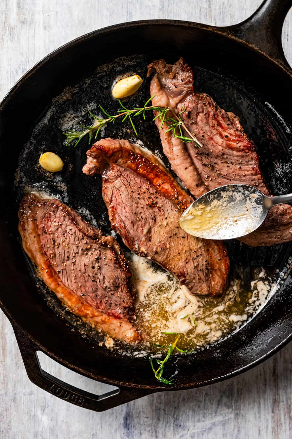 Basting steaks with butter while cooking them in a cast iron skillet.