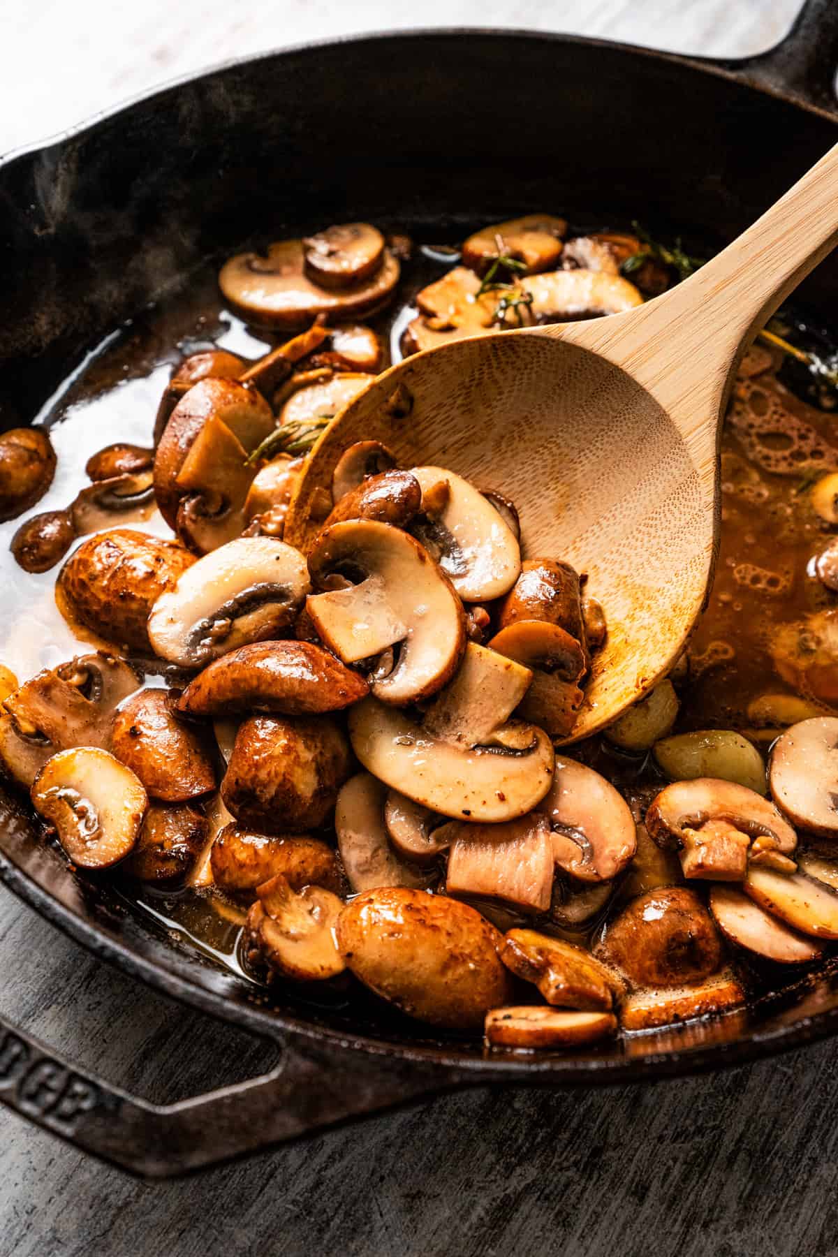 Stirring mushrooms as they cook in a skillet.