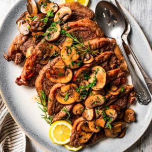 Coulotte steak on a serving platter, topped with mushrooms.