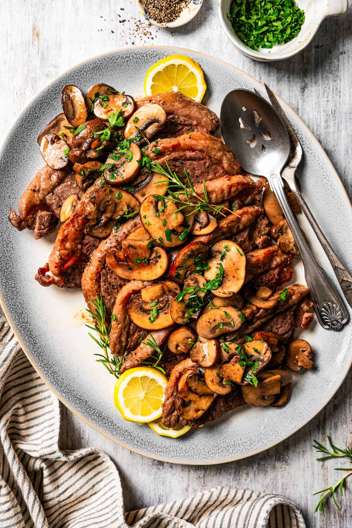 Coulotte steak on a serving platter, topped with mushrooms.