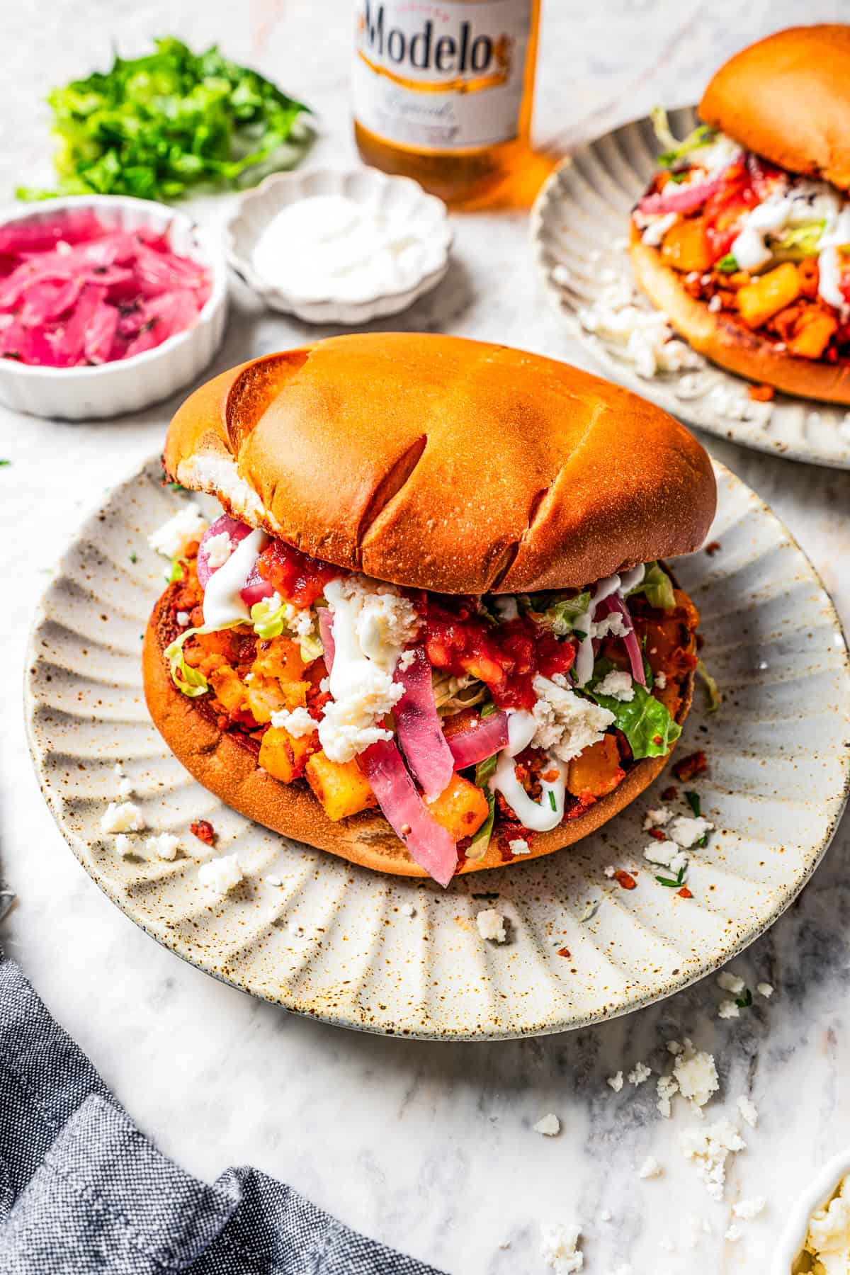 Pambazo sandwich served on a plate, with bowls of sandwich fixings placed around it.