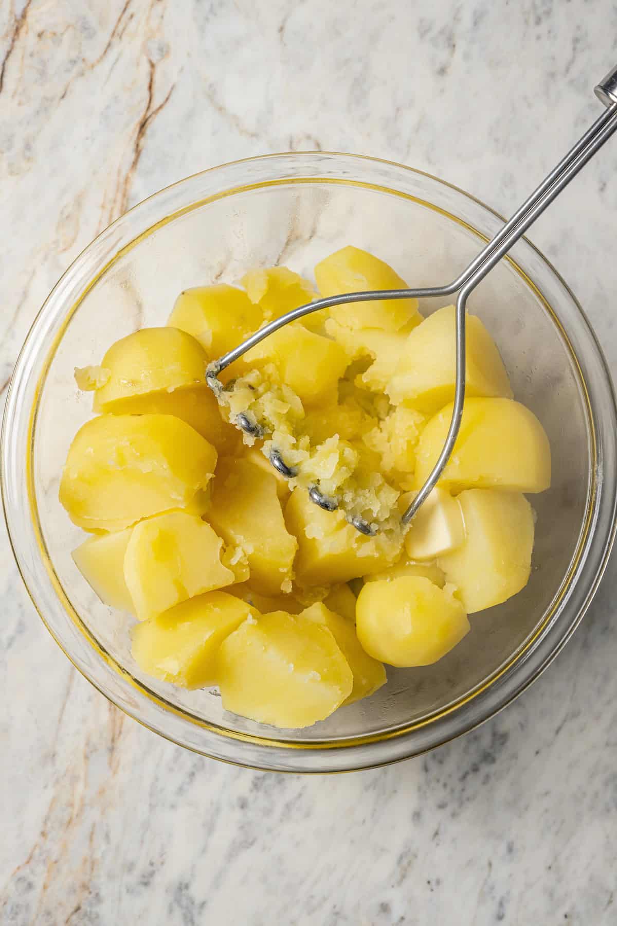 Mashing cooked potatoes with butter.