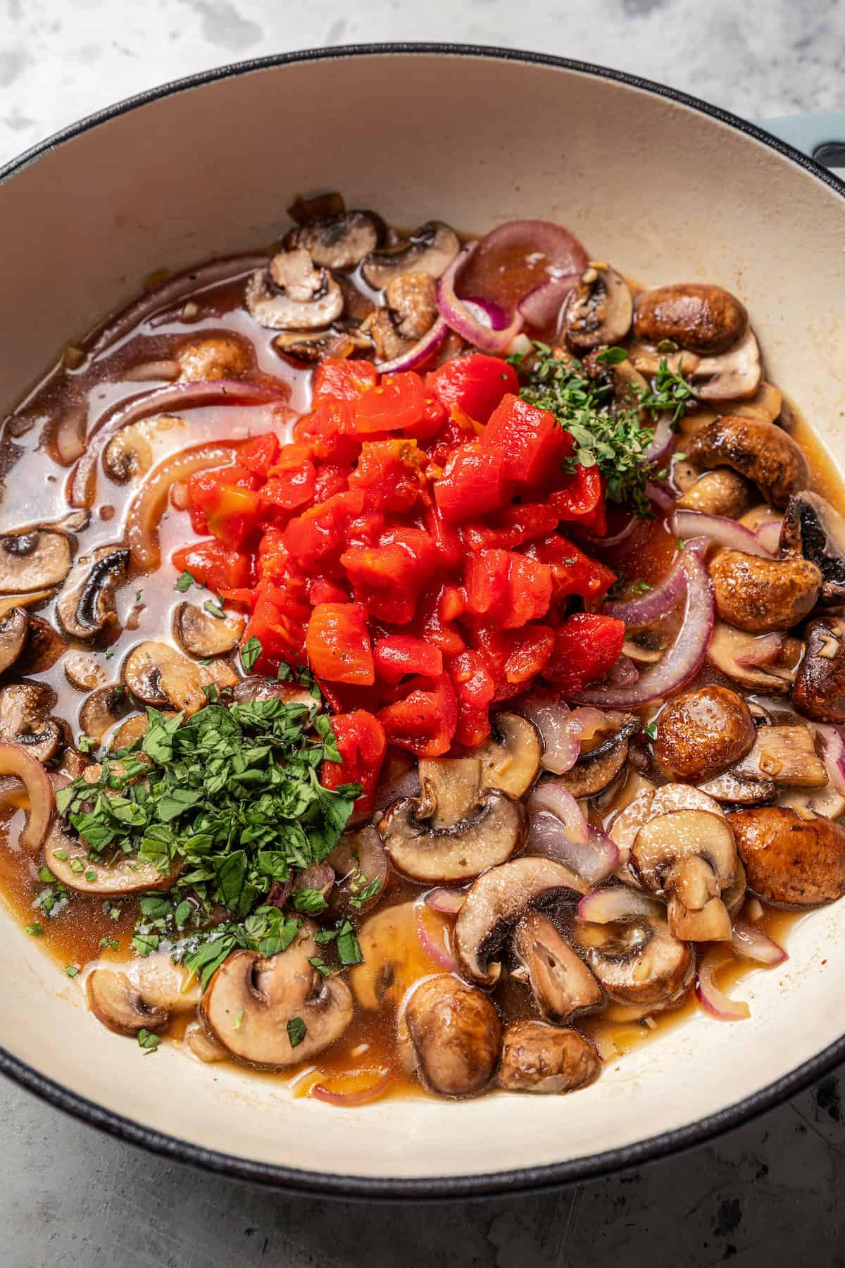 Adding tomatoes and herbs.