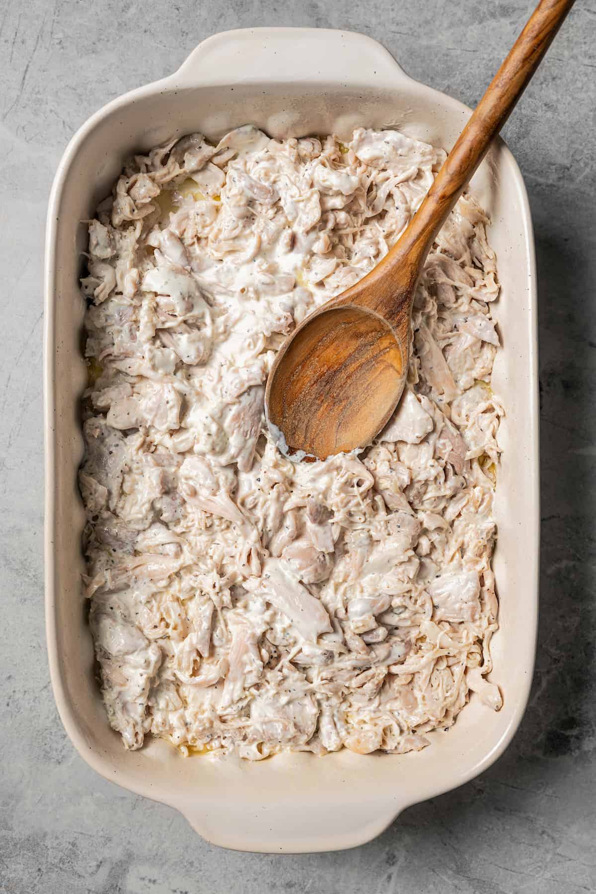 Adding the chicken layer to the baking dish.