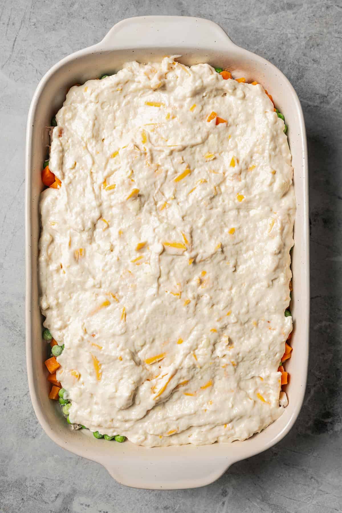 Adding veggies and biscuit layer to the baking dish.