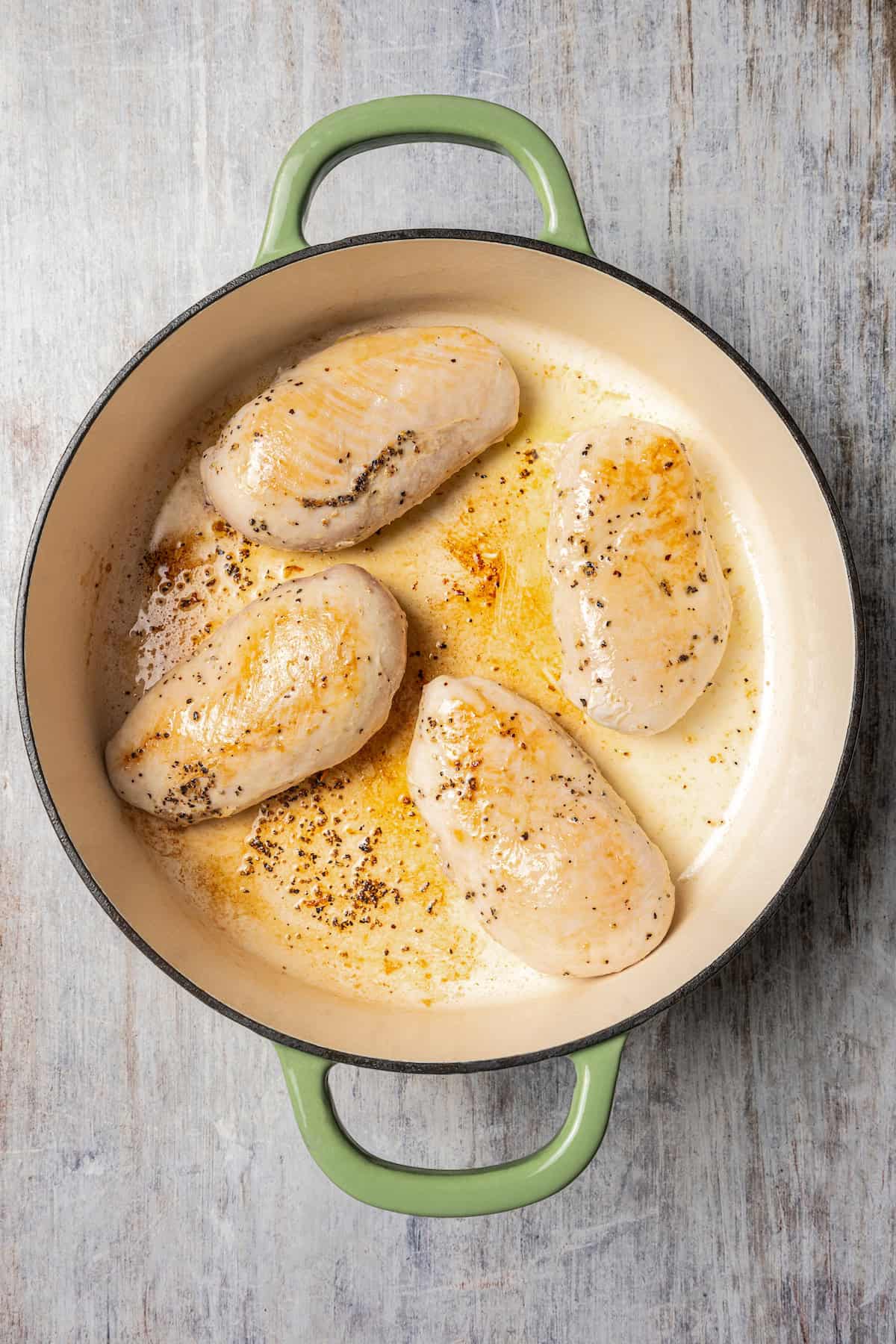 Searing chicken breasts in a cooking pot.