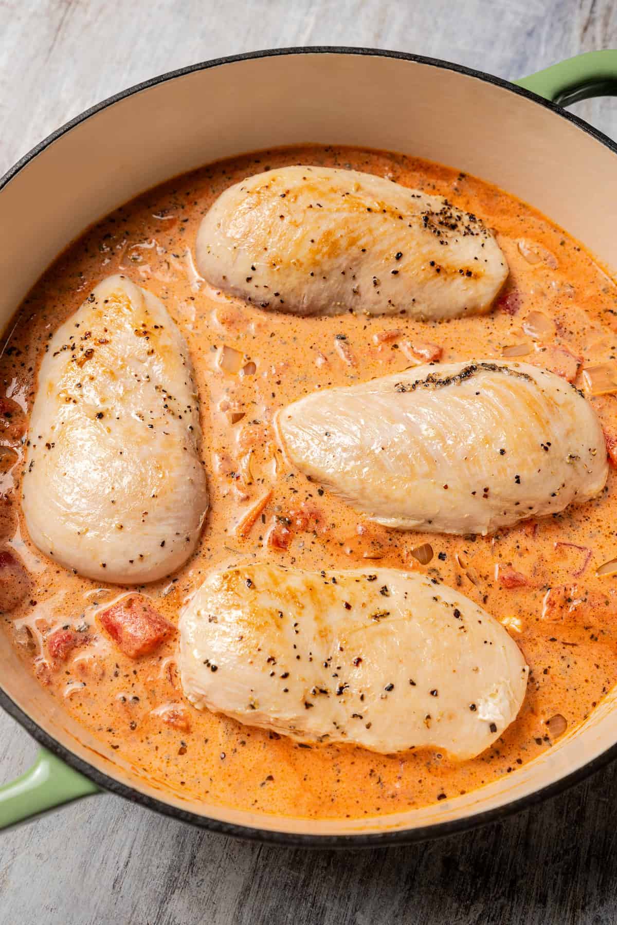 Adding chicken to the tomato sauce.