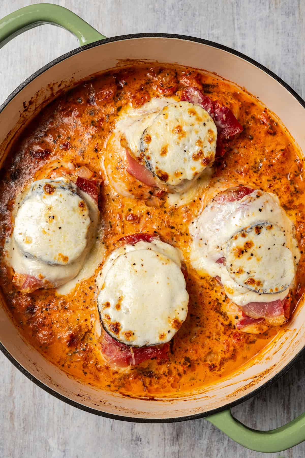 Melting cheese on top of eggplant and chicken in tomato sauce.