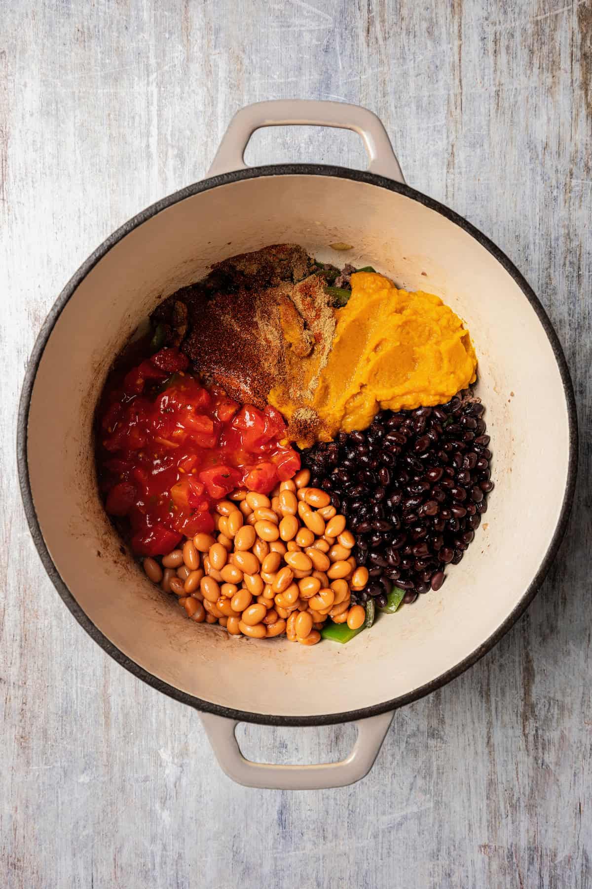 Pumpkin chili ingredients combined in a pot.