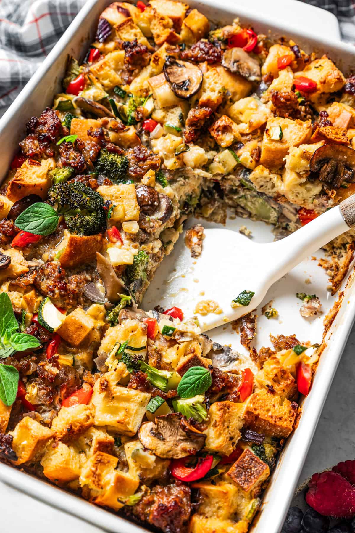 A spatula resting in an open space in breakfast casserole where a slice has been served.